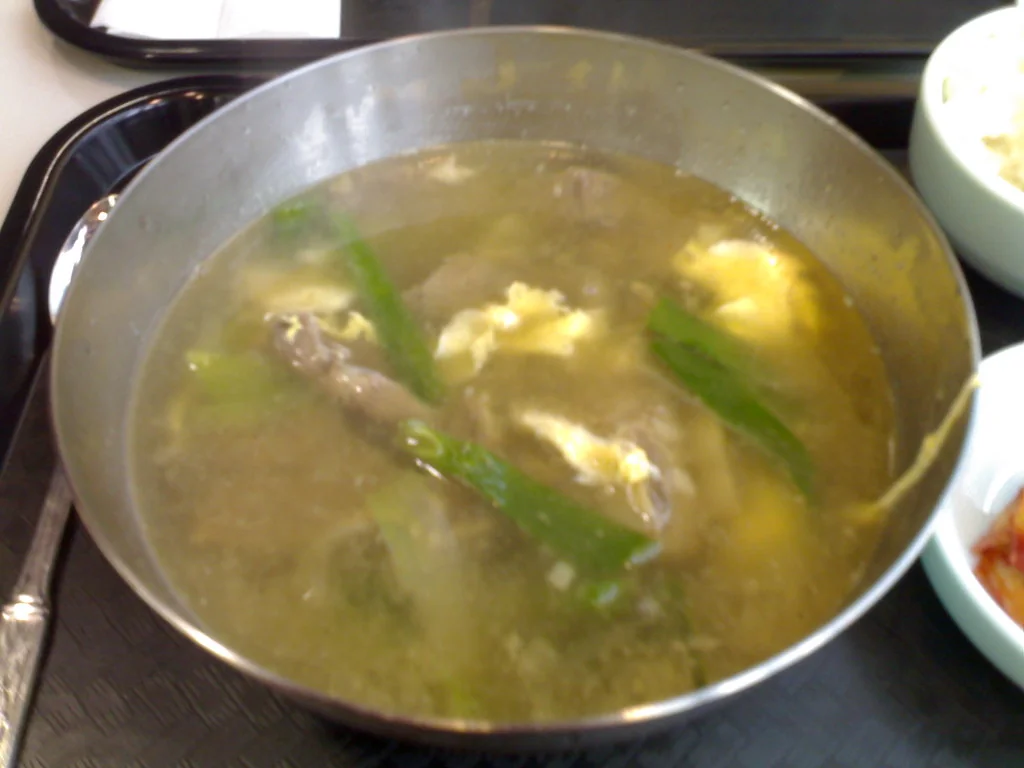 스테인리스 냄비에 담긴 갈비탕 국물과 달걀 지단, 대파